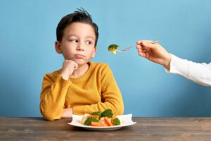 Unhealthy Child is very unhappy with having to eat vegetables. There is a lot of vegetables on his plate. He hates vegetables.