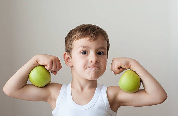 nutrition boy with green apples showing biceps face
