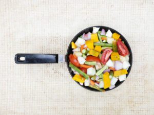 a frying pan full of cut healthy vegetables like tomato, onion, cucumber, drumstick and pumpkin arranged before cooking mistakes